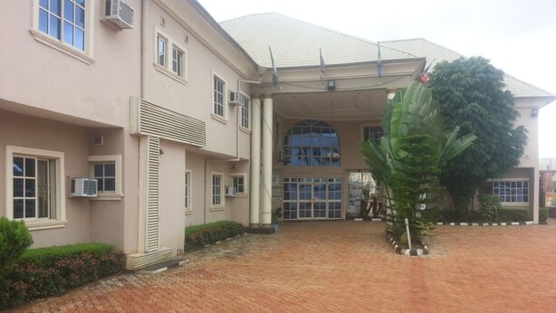 A building with a covered entrance, air conditioning units, and a paved driveway. - Definite Destiny Asaba (Asaba)
