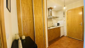 A compact kitchen with wooden cabinets, a microwave, and a sink. - Snow Comfort Edificio Monte Gorbea (Monachil)