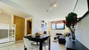 A modern living room with a dining area, a sofa, a coffee table, and a window with a view. - Snow Comfort Edificio Monte Gorbea (Monachil)