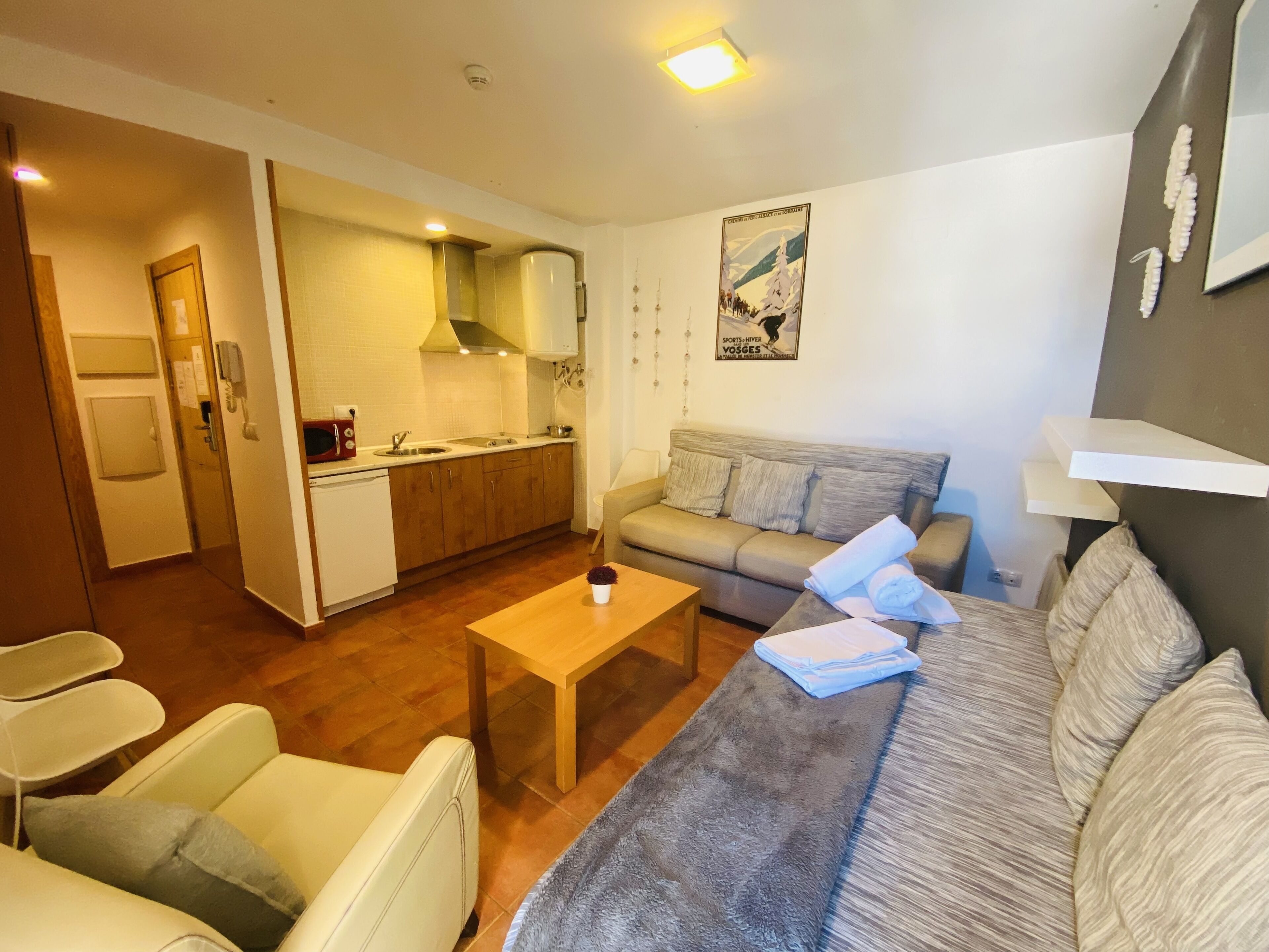 A compact living space with a kitchenette, a sofa, a coffee table, and a dining table.