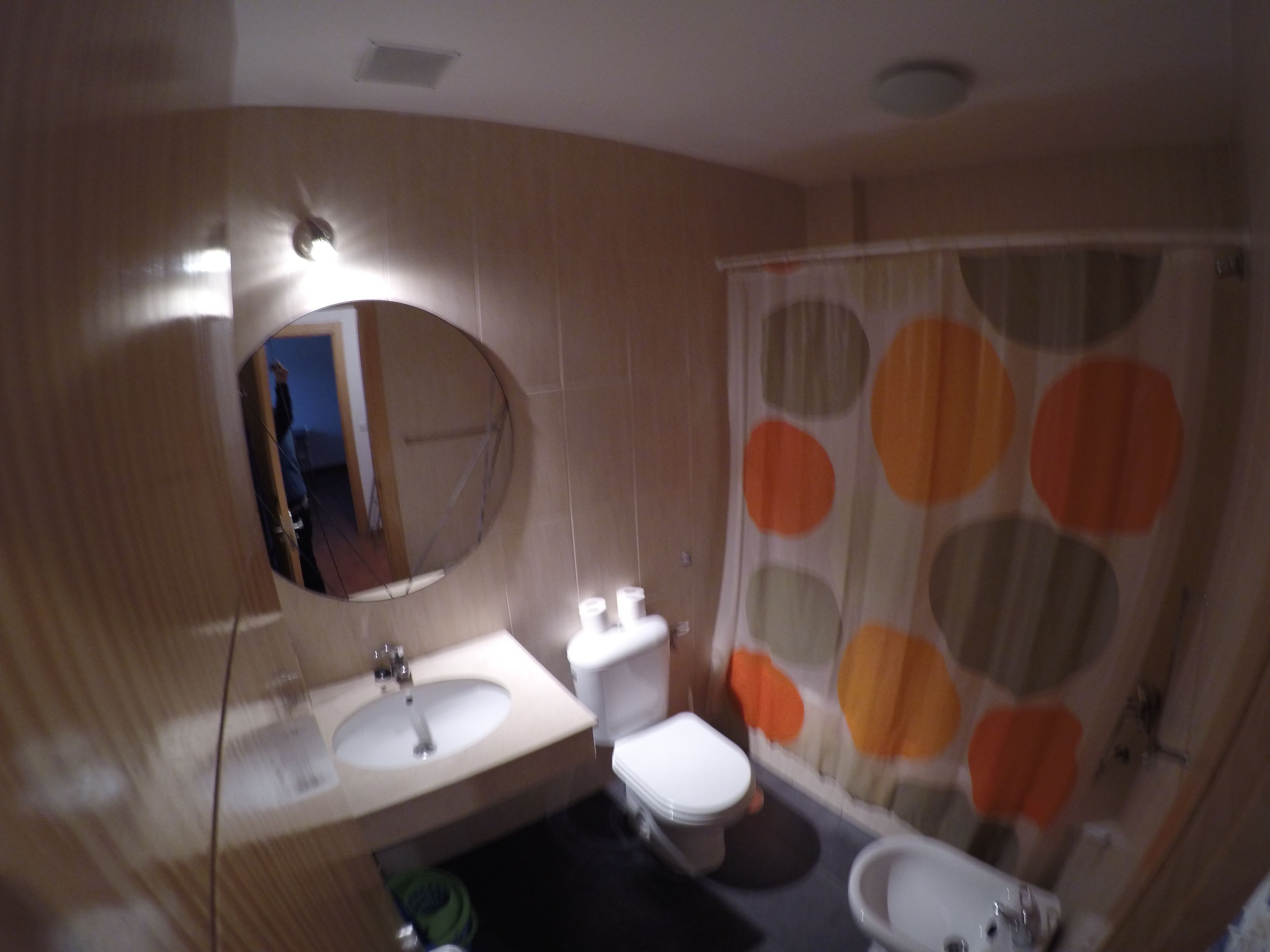 Een badkamer met een wastafel, toilet en douchegordijn met stippen.