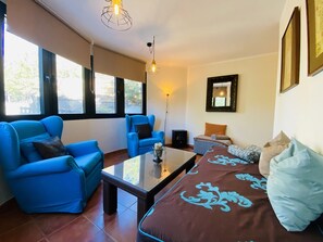 A living room with a sofa, armchairs, a coffee table, and a bed with a patterned bedspread. - Snow Comfort Edificio Monte Gorbea (Monachil)