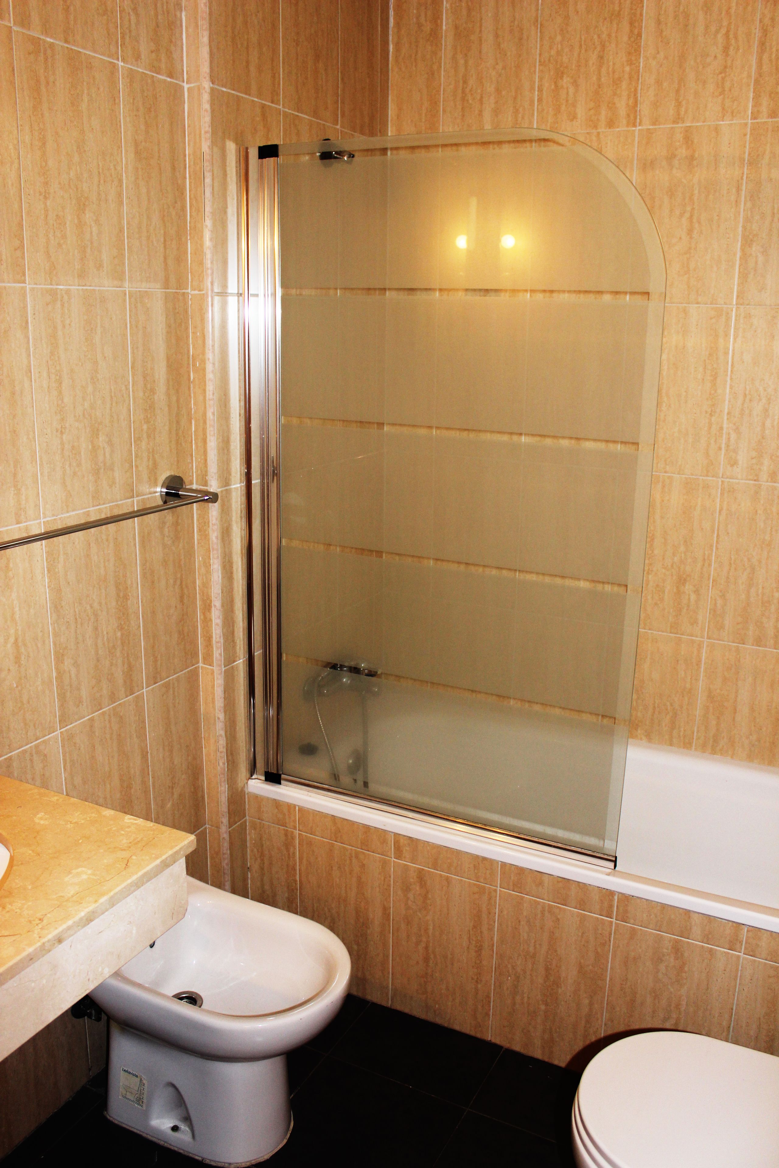 A bathroom with a glass-enclosed shower, a toilet, and a bidet.