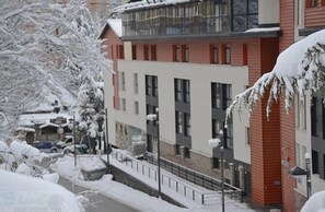 A multi-story building with a red and white facade, multiple windows, and a balcony. - Snow Comfort Edificio Monte Gorbea (Monachil)