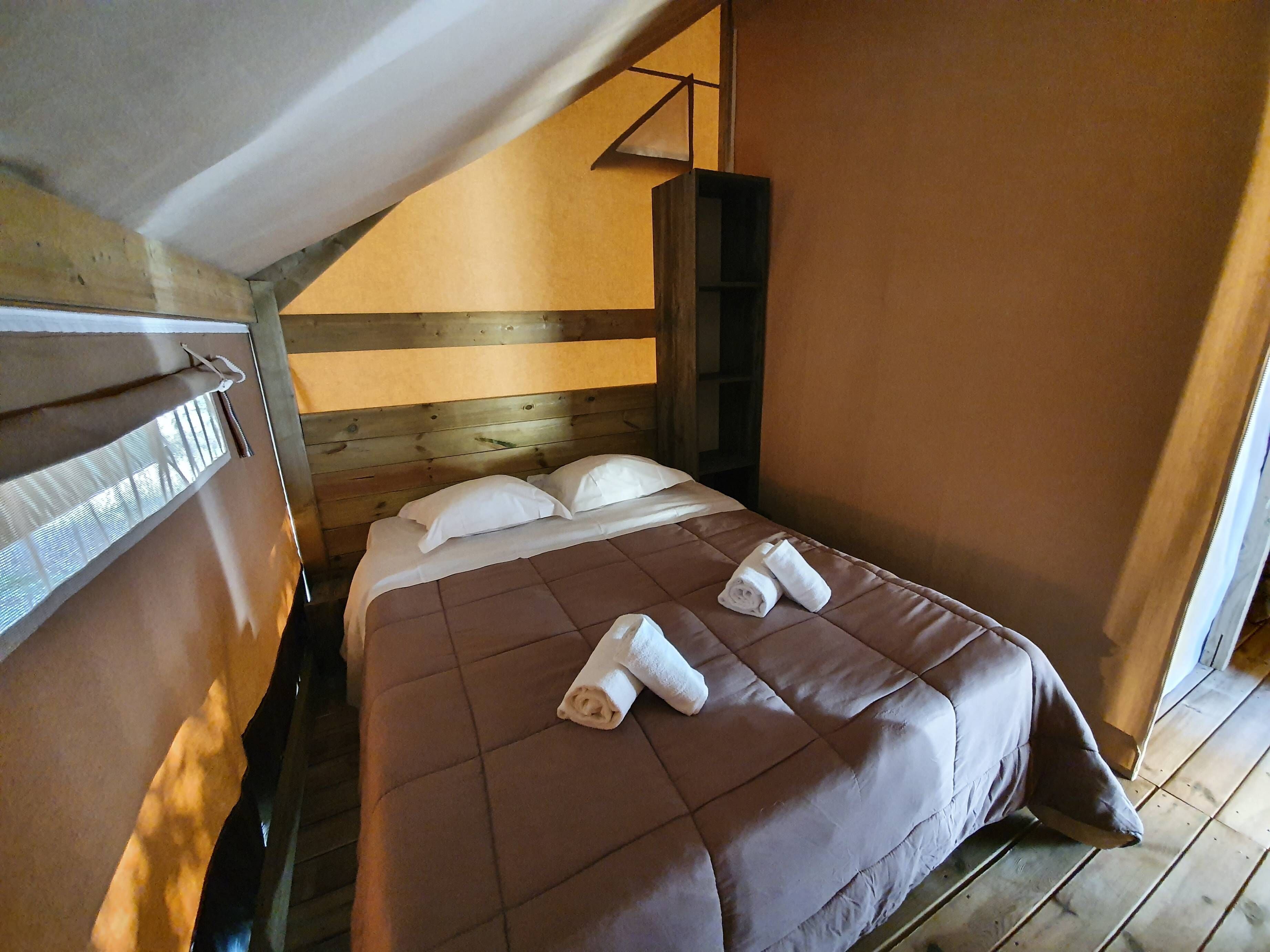 Ein kleiner, gemütlicher Raum mit einem Einzelbett, Holzwänden und einer schrägen Decke.