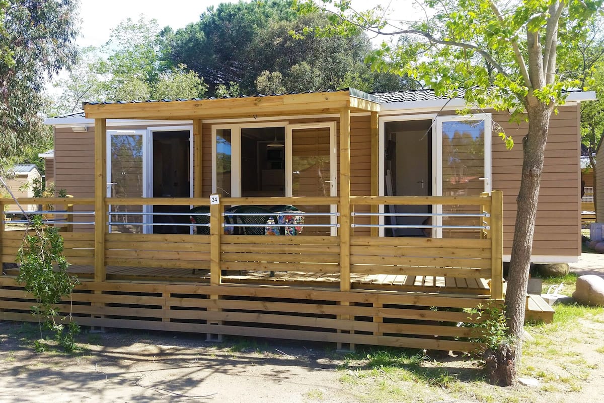 A wooden cabin with a fenced porch, a sliding door, and a window.