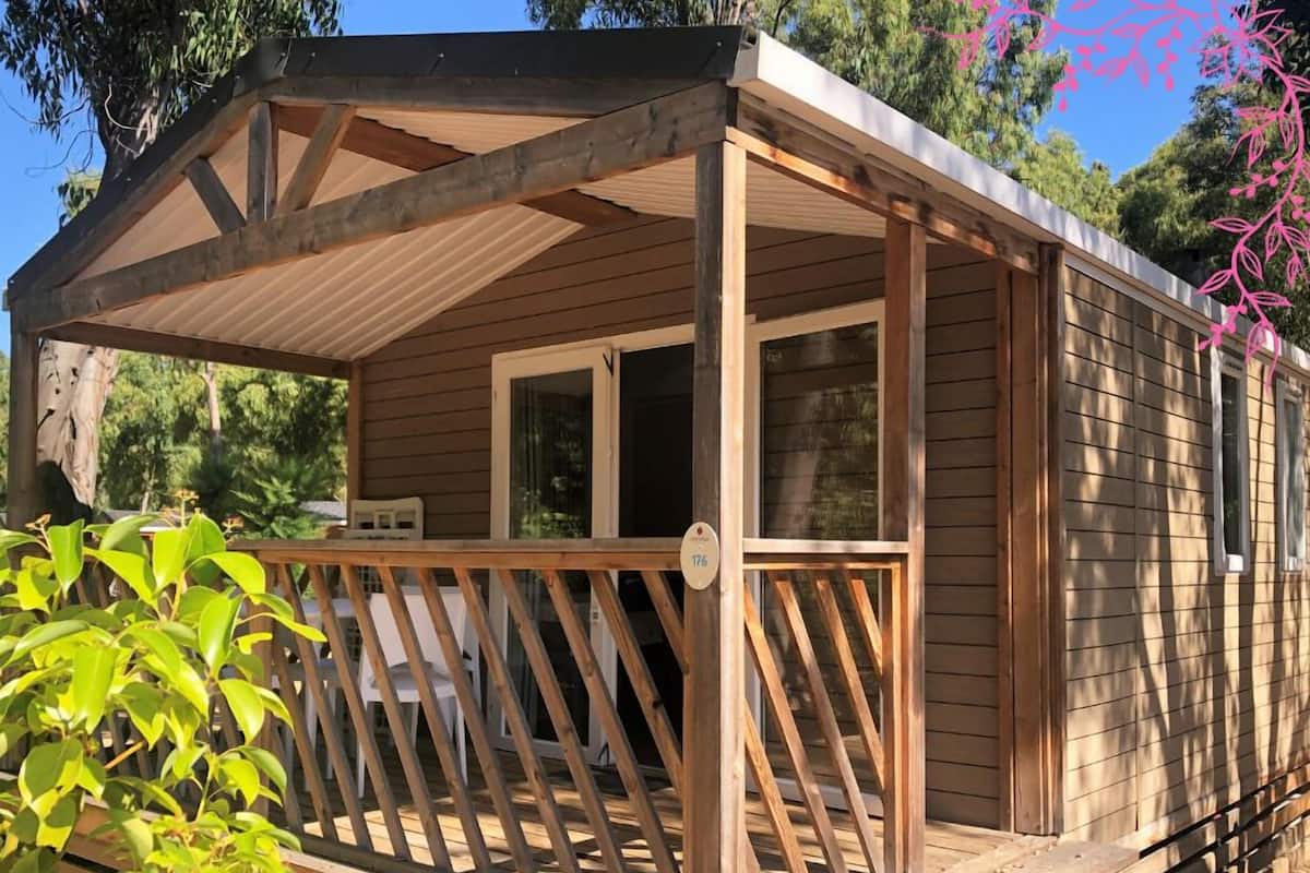A wooden cabin with a balcony, a window, and a door.
