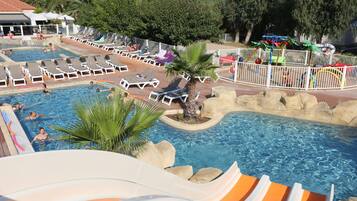 A pool area with multiple water slides, lounge chairs, and a palm tree.