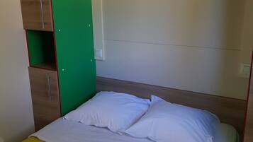 A single bed with white bedding, a green wall panel, and a wooden headboard.