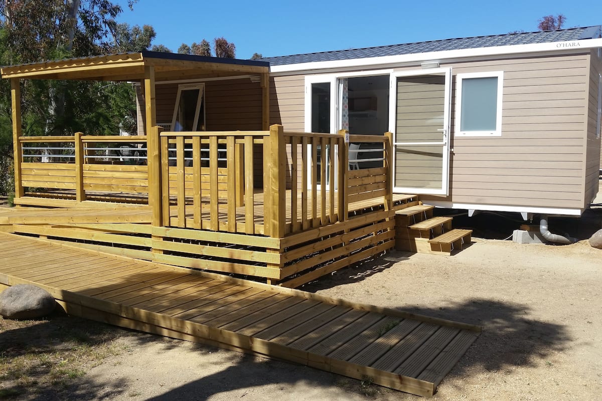 A mobile home with a wooden deck and a covered porch area.