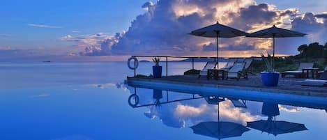 Een buitenzwembad, een infinity pool, parasols voor strand/zwembad