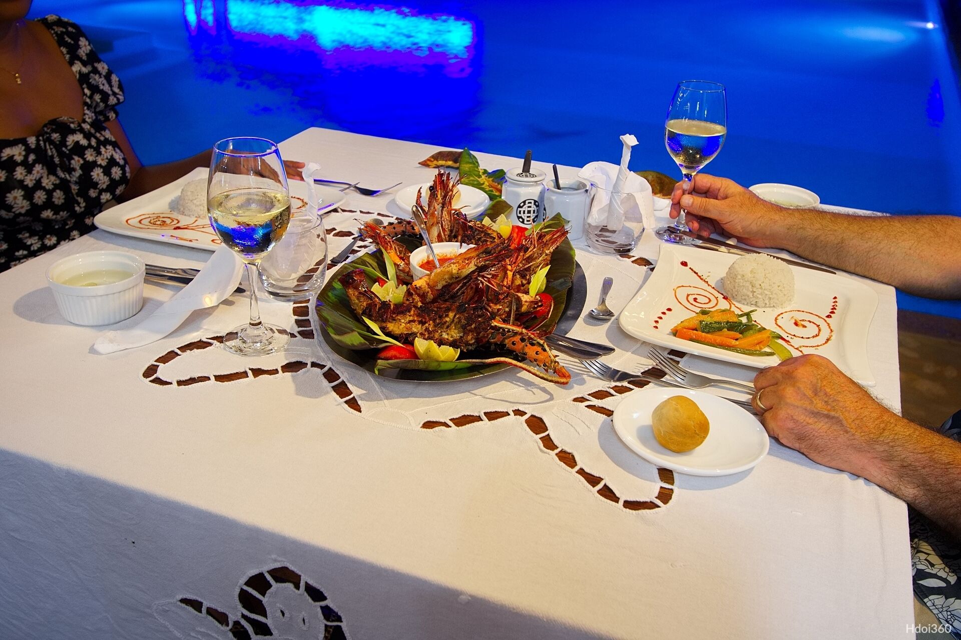 A dining table with seafood dishes, wine glasses, and a decorative plate.