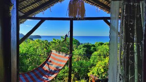 Una habitación con vista al océano, una hamaca y un banco.