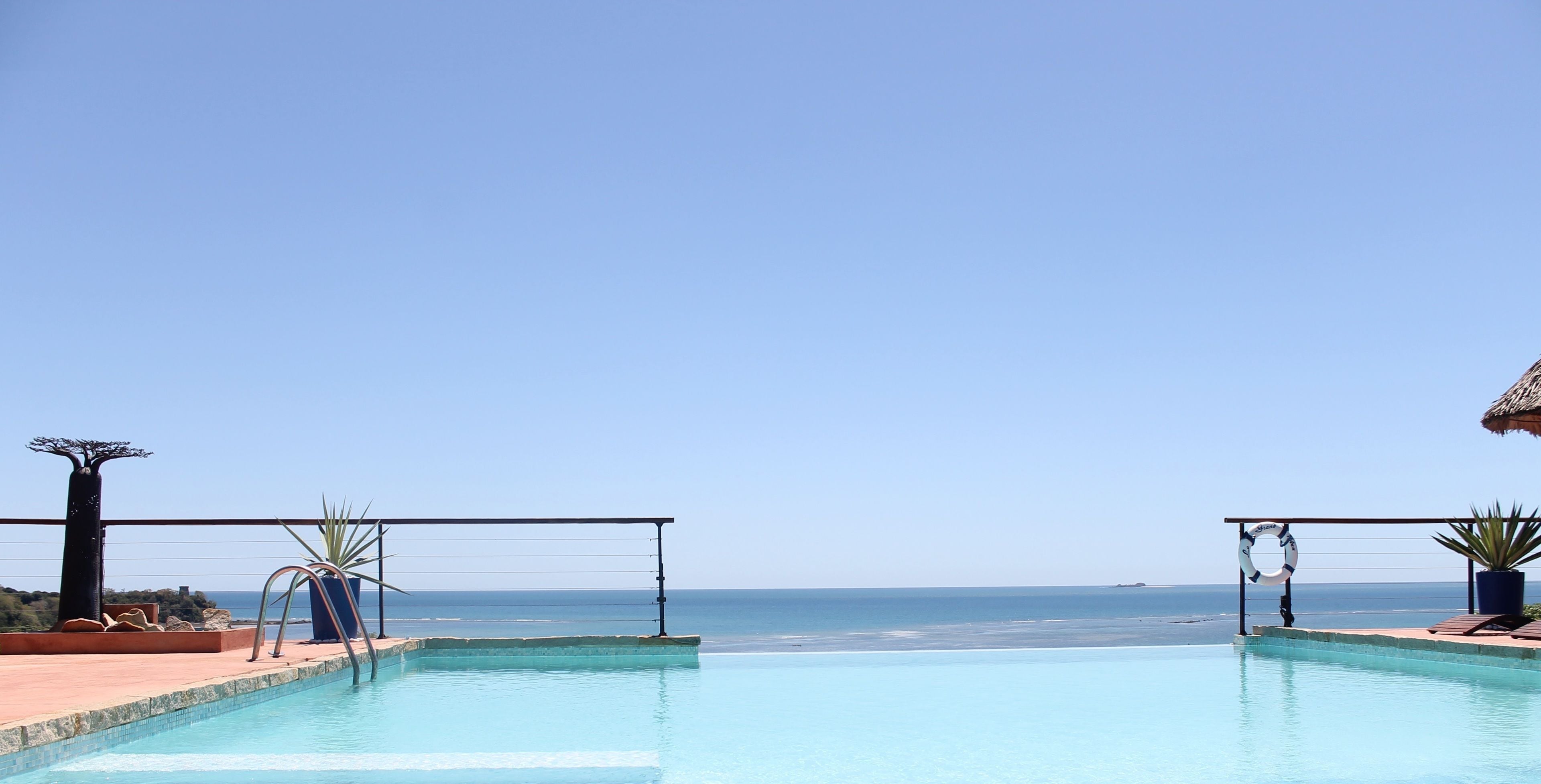 outdoor pool, an infinity pool, pool umbrellas, pool loungers