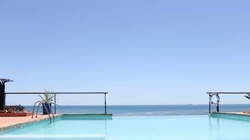 Outdoor pool, an infinity pool, pool umbrellas, sun loungers