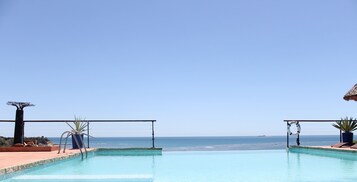 Outdoor pool, an infinity pool, pool umbrellas, sun loungers