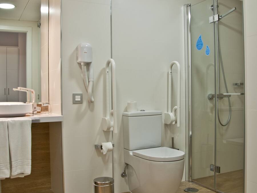 A modern bathroom with a toilet, bidet, and glass shower enclosure.