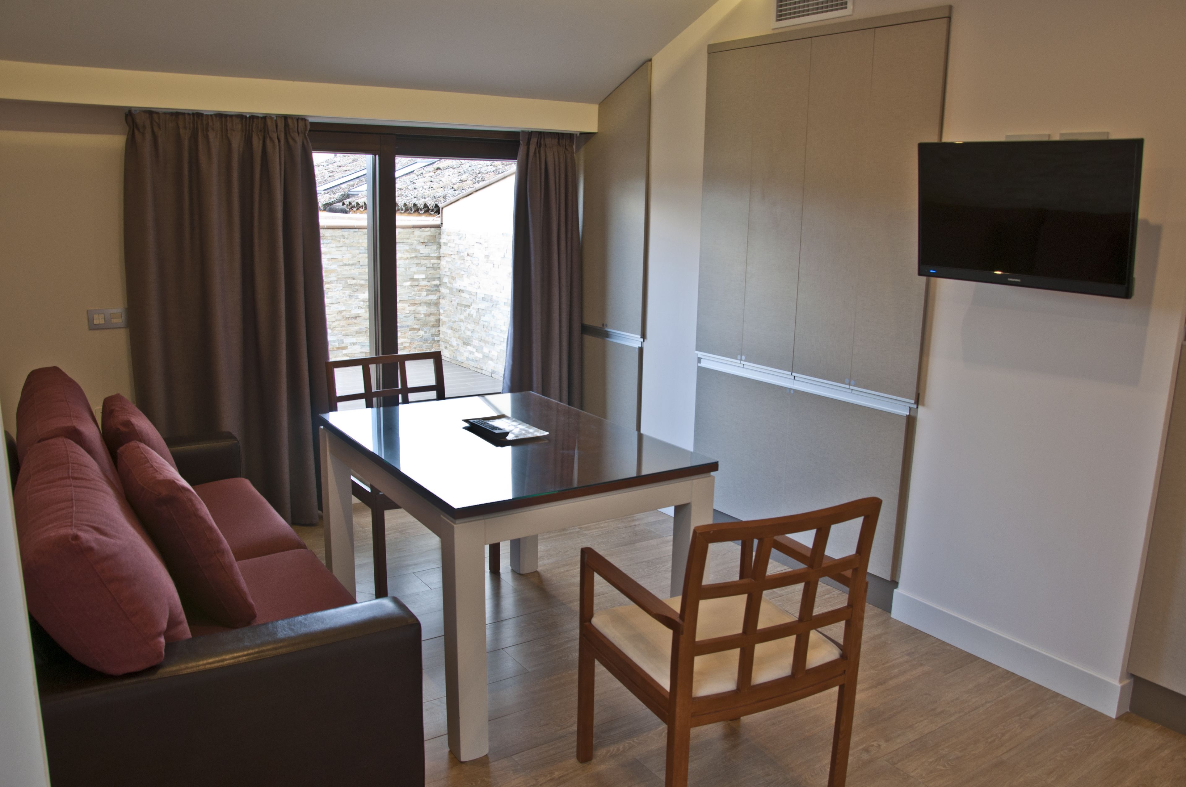 Un espacio habitable compacto con una mesa de comedor, un sofá y un televisor montado en la pared.