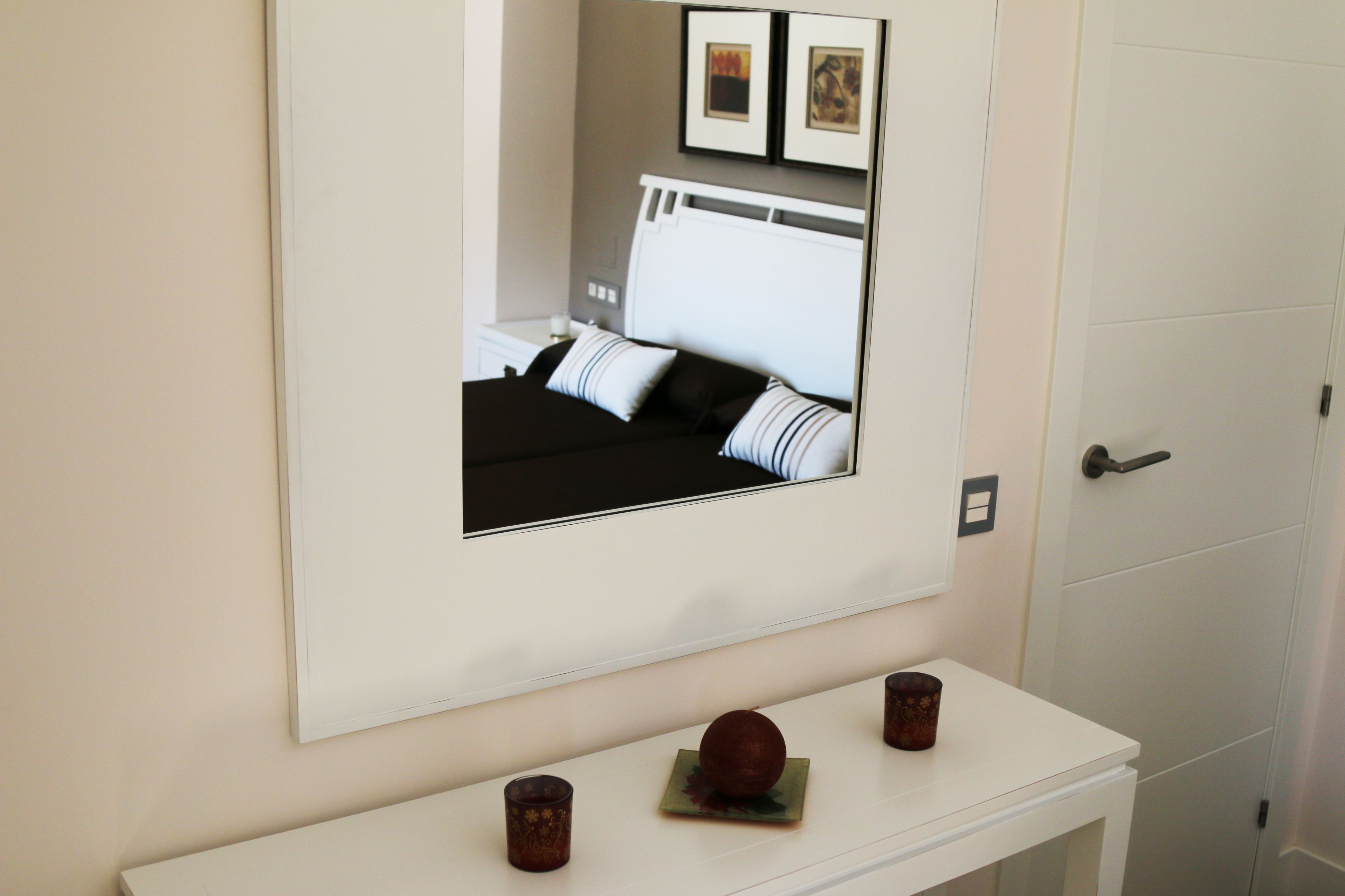 A bedroom with a bed, a bedside table, and a mirror.