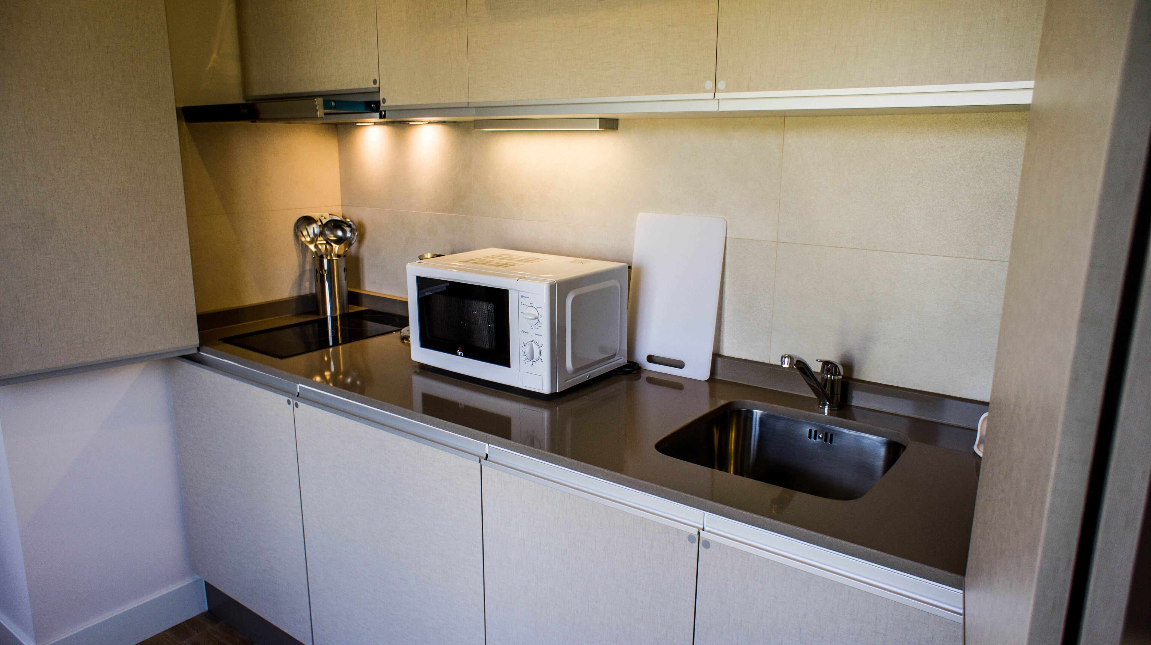 A kitchen with a microwave, a sink, and a stovetop.