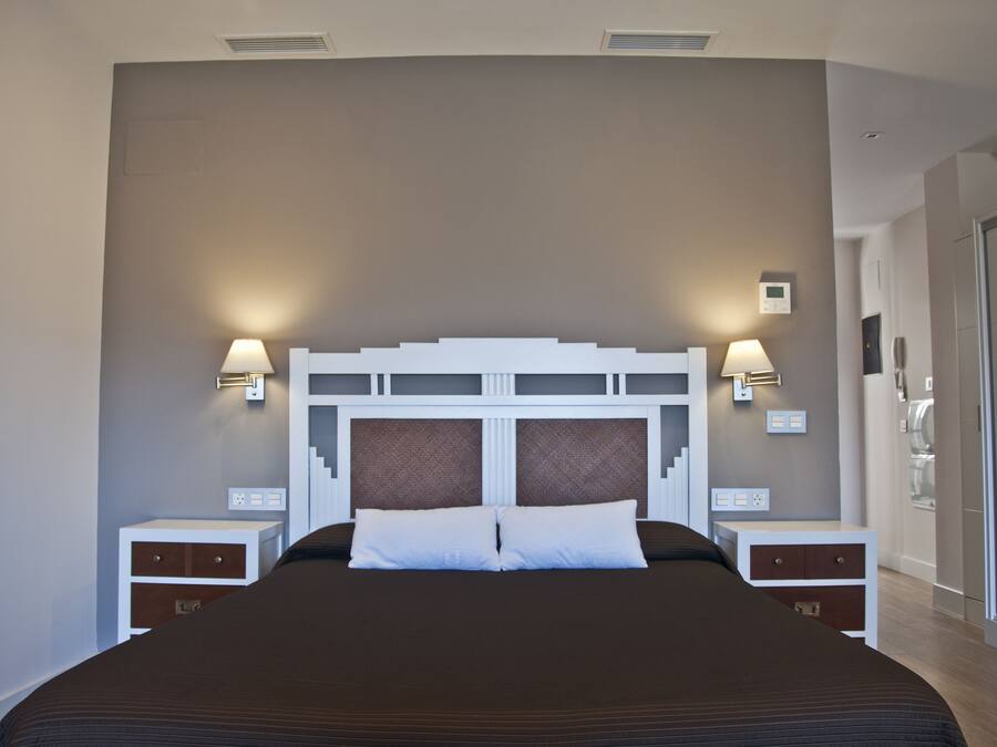 Ein modernes Hotelzimmer mit einem großen Bett, zwei Nachttischen und Wandleuchten.