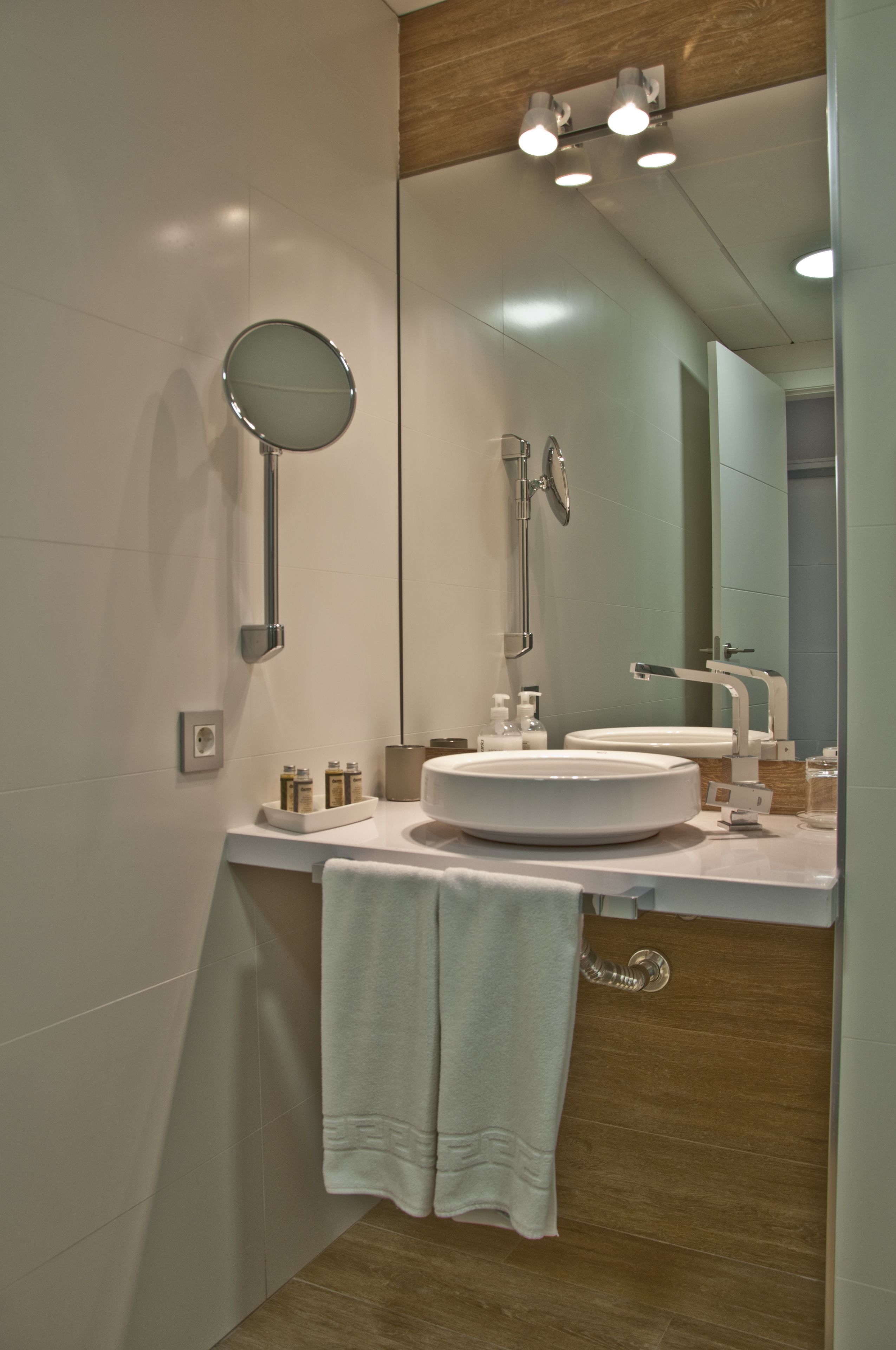 A modern bathroom with a round mirror, a sink, and a shower.