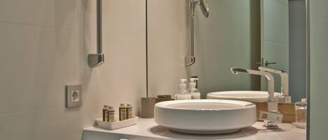 A modern bathroom with a round mirror, a sink, and a shower.