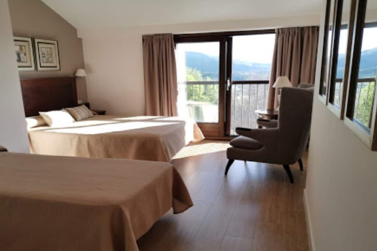 A hotel room with two beds, a chair, and a balcony with a view.