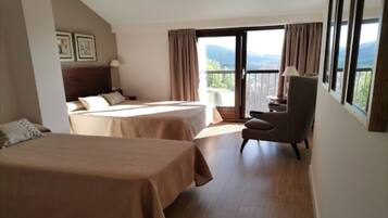 A hotel room with two beds, a chair, and a balcony with a view.