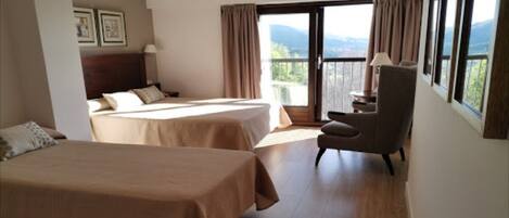 A hotel room with two beds, a chair, and a balcony with a view.