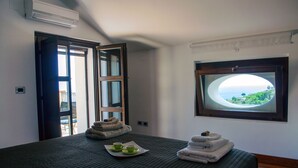Habitación de hotel con cama, ventana con vistas y puerta que da a un espacio exterior.