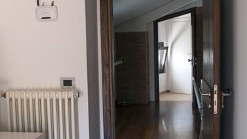 Un corridoio con termosifone, una porta e vista su un'altra stanza.