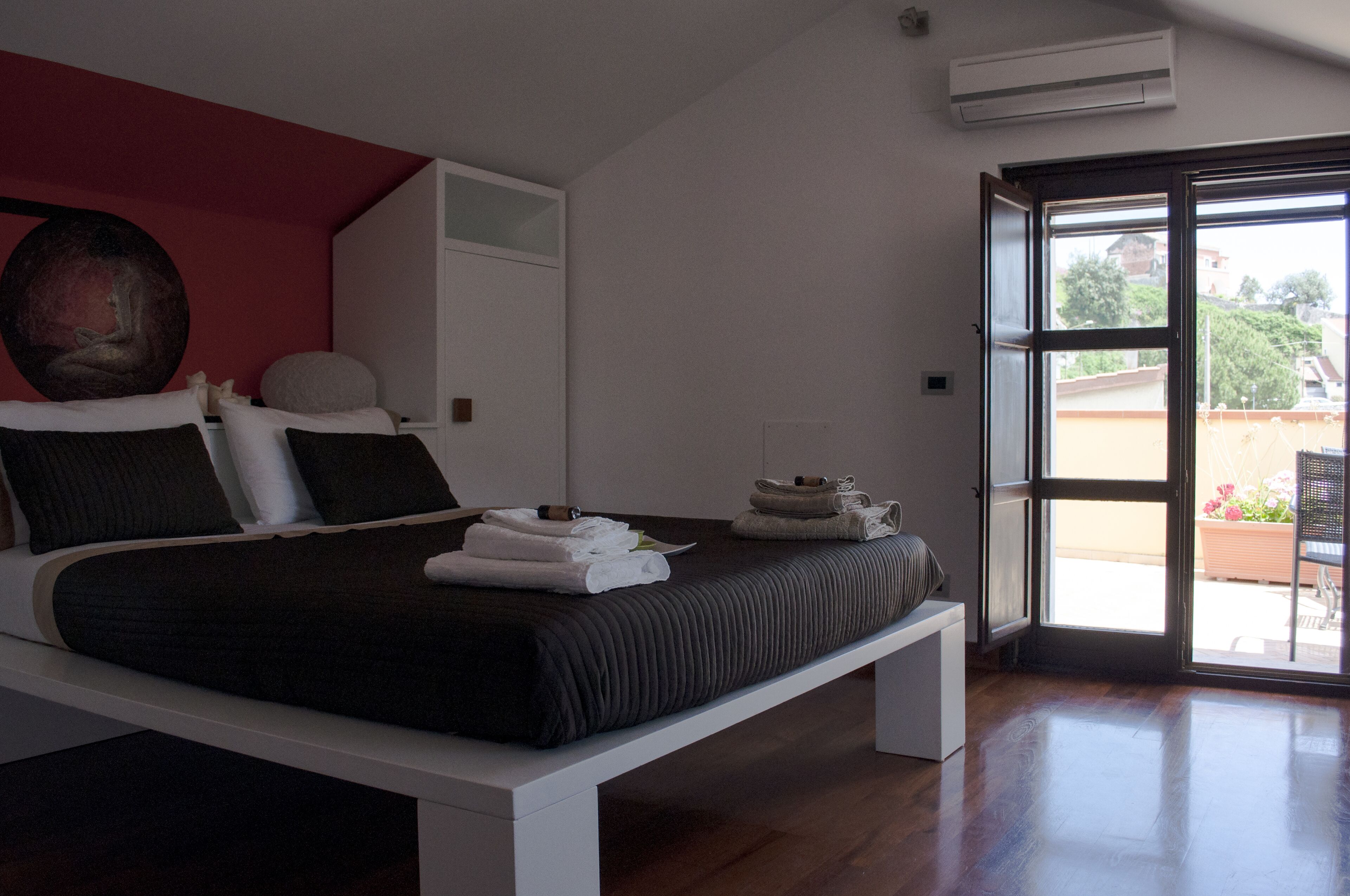 Ein modernes Schlafzimmer mit einem Bett, einem großen Gemälde und Blick durch eine offene Tür.
