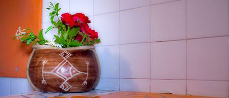 A potted plant with red flowers on a tiled floor.