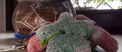 A set of keys, a crocheted bag, and a ceramic pot on a countertop with a window view of purple flowers.