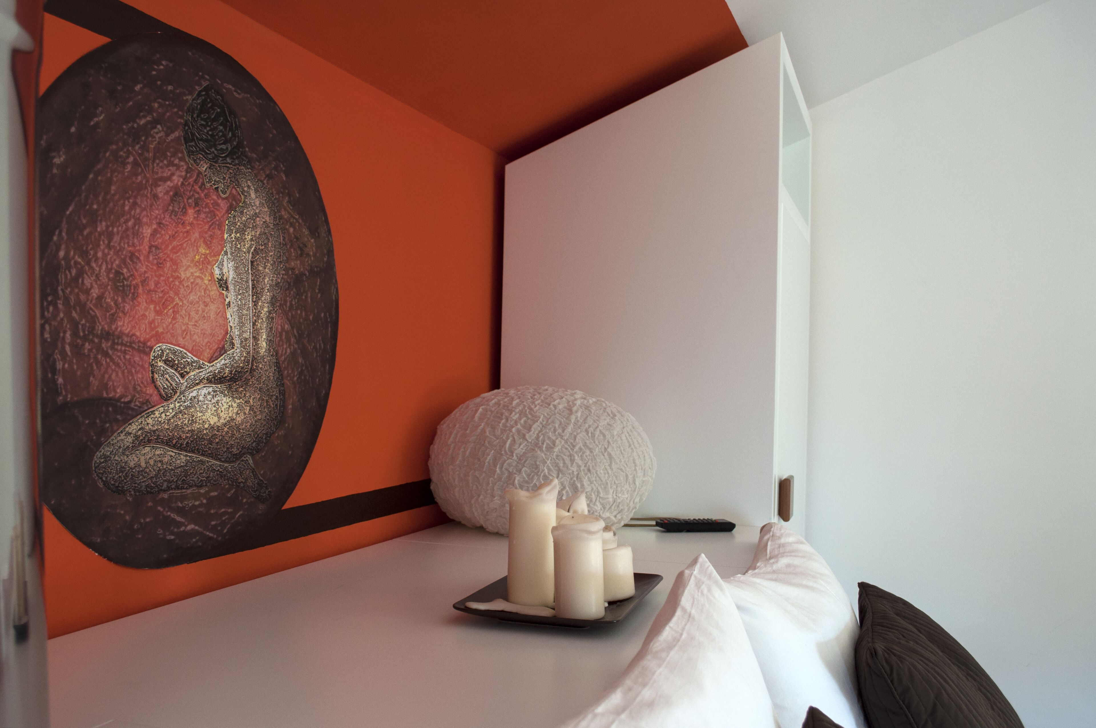 A bedroom with a bed, a painting, and candles.
