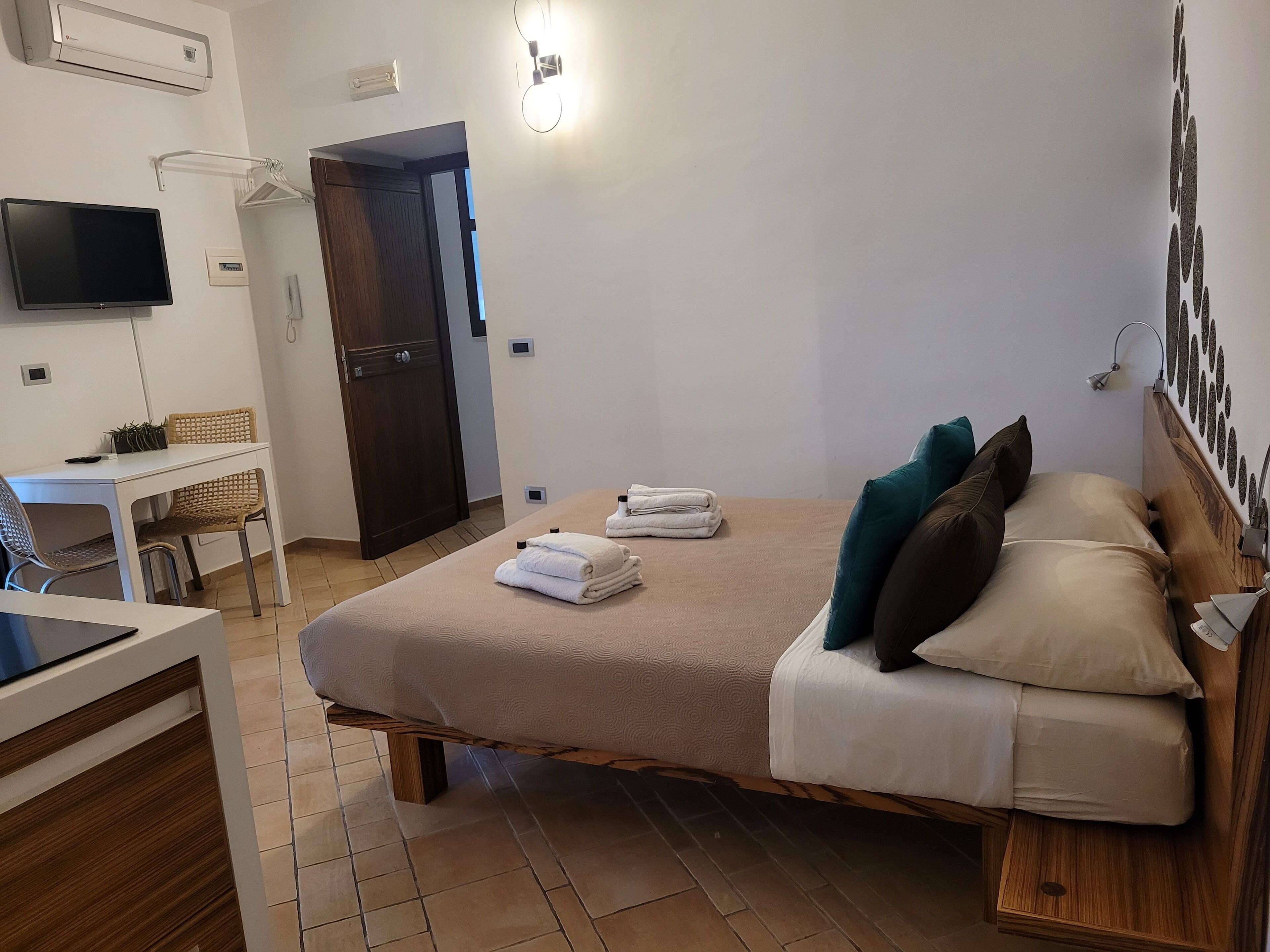 Habitación de hotel con una cama, un escritorio, una silla, un televisor y una puerta.