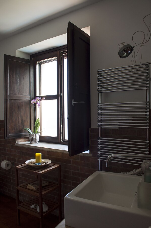A bathroom with a window, a sink, and a towel rack.