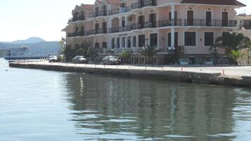A multi-story hotel with balconies, a waterfront view, and a dock with boats.