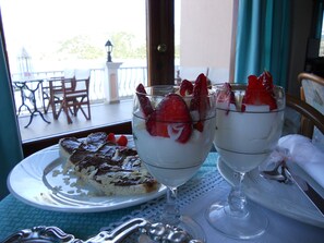 A dessert table with two glasses of dessert and a slice of cake on a plate. - Miramare Hotel (Kefalonia)