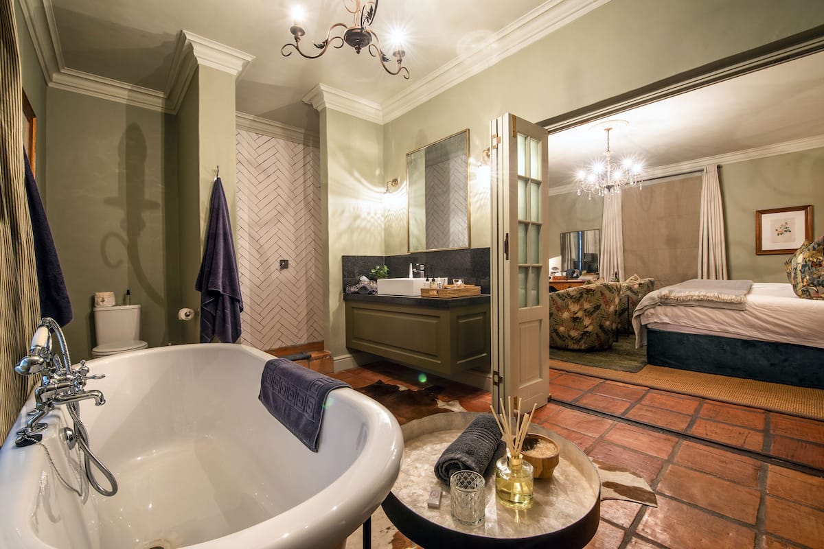 A bathroom with a large bathtub, a sink, and a mirror. There is a toilet and a shower visible in the background.