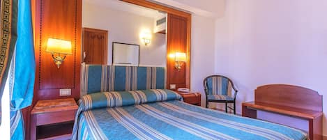 A bedroom with a large bed, two bedside tables, a chair, and a wooden headboard.