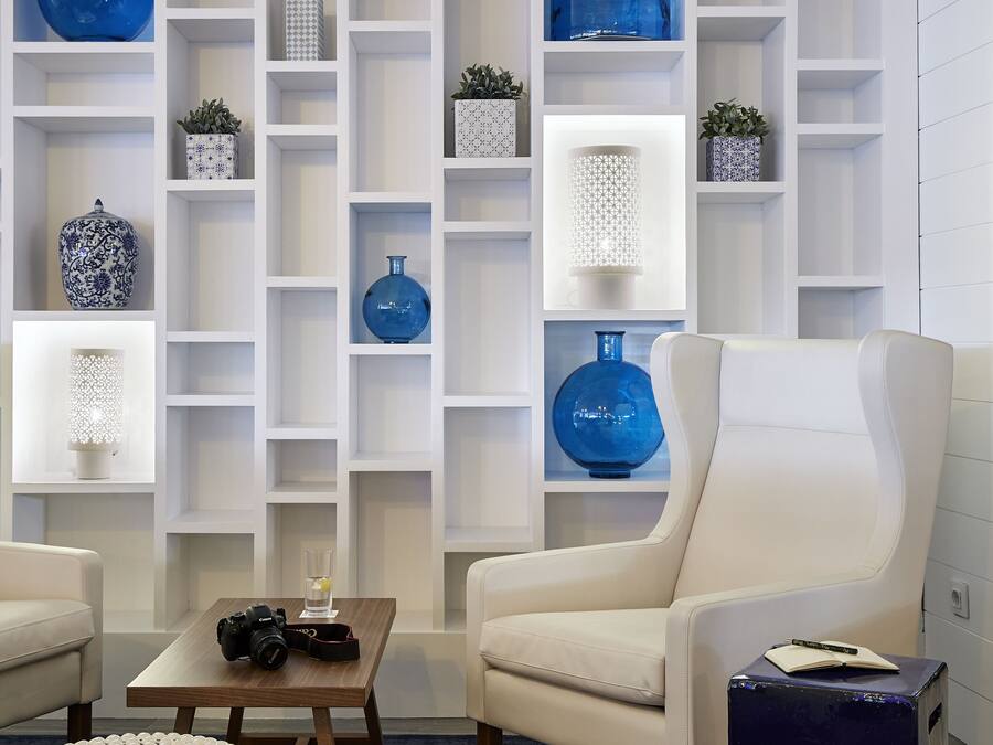 Una sala de estar moderna con un sofá blanco, una mesita de centro y una estantería llena de objetos decorativos.
