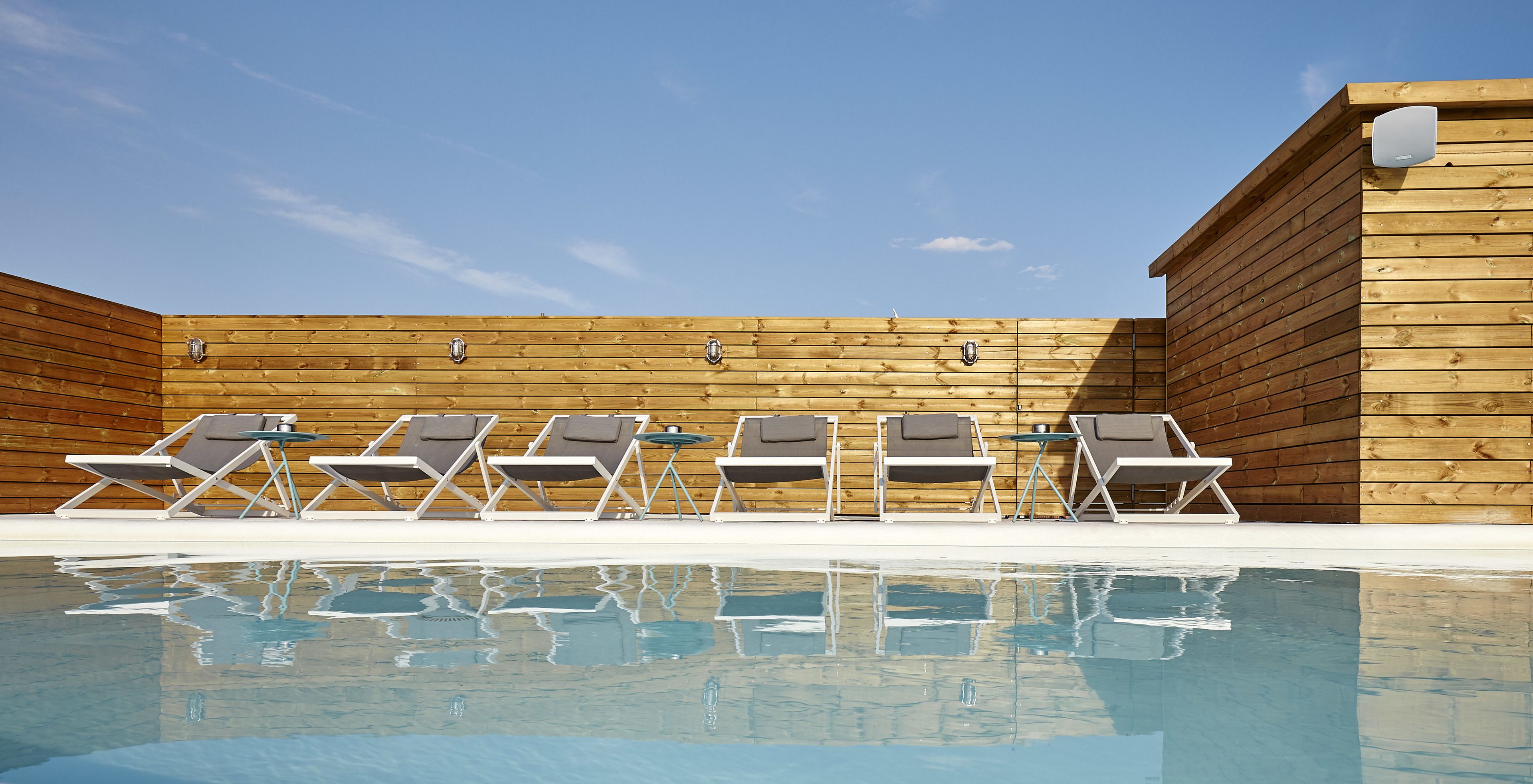 A poolside area with lounge chairs and a wooden wall.