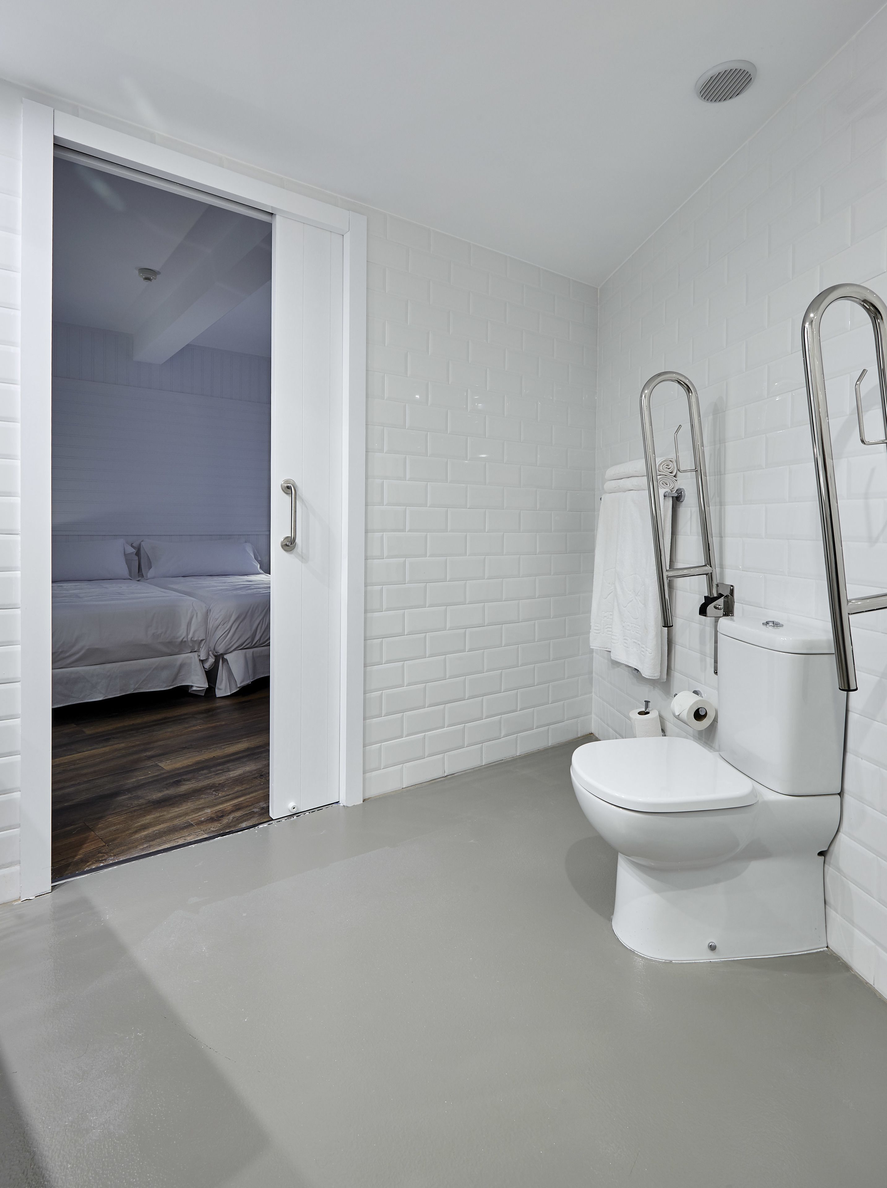 A modern bathroom with white subway tiles, a white toilet, and a shower with a chrome faucet.