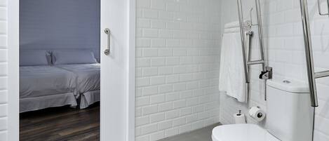 Un baño moderno con azulejos blancos tipo metro, inodoro blanco y ducha con grifo cromado.