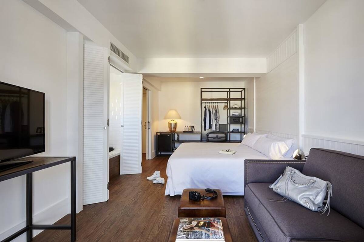 Une chambre d’hôtel comprenant un lit, un canapé, une télévision, un bureau et une armoire.