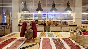Un comptoir de charcuterie où sont présentées différentes sortes de viandes et de fromages, disposés sur des plateaux.