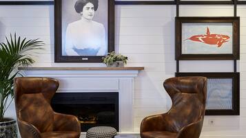 A modern living room with two leather armchairs, a fireplace, and framed artwork on the wall.