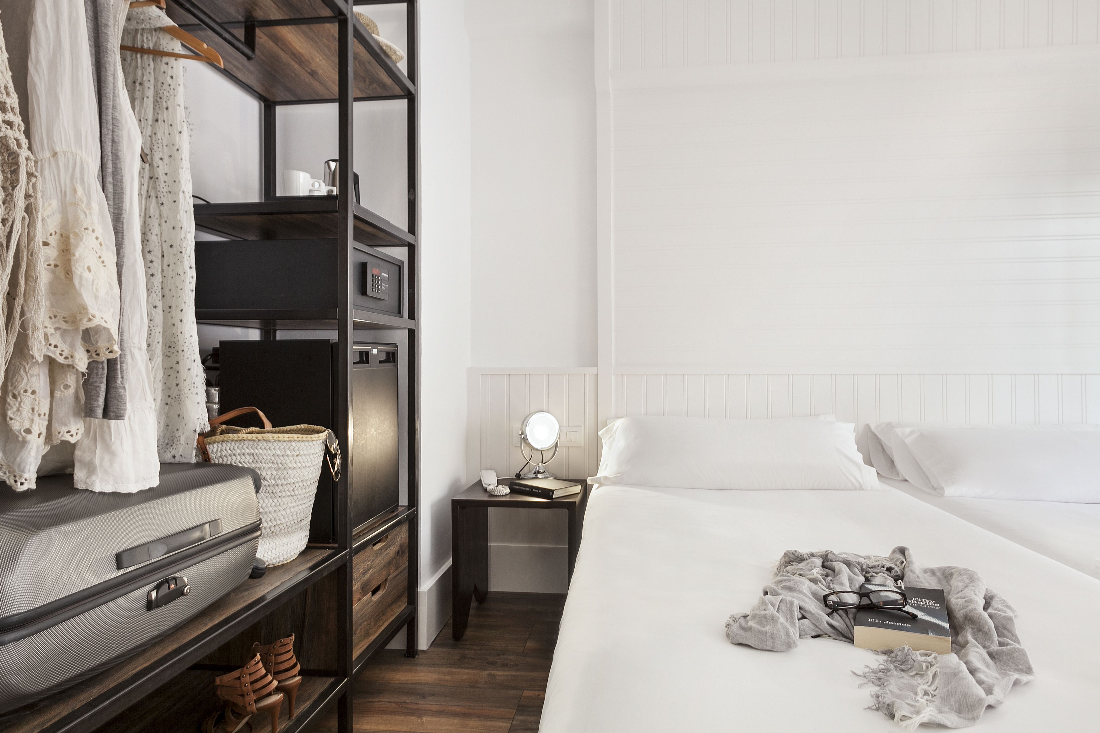 A neatly organized bedroom with a bed, a nightstand, a wardrobe, and a suitcase.